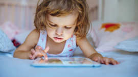43578707 - little girl playing tablet at home on a bed
